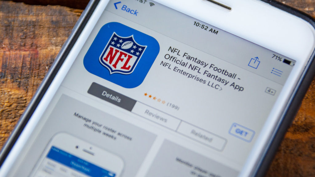 Patron visiting bars for fantasy football draft looking at closeup image of phone displaying NFL Fantasy Football app 