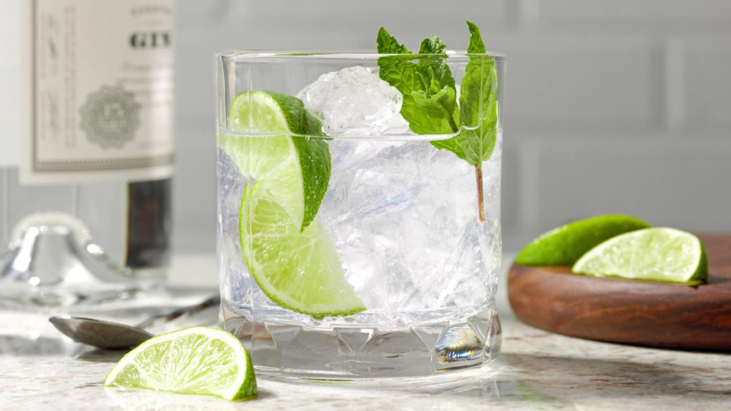 Photo of a gin and tonic with lime showing off gin and herbs.