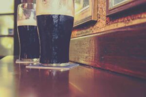 Two glasses of famous black Irish stout in Irish pub on wooden bar